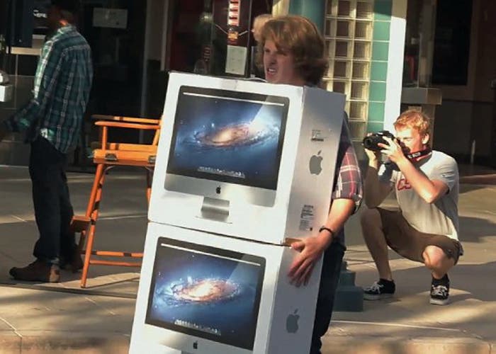 Un patoso joven transporta dos iMac sabiéndo que será el centro de todas las miradas